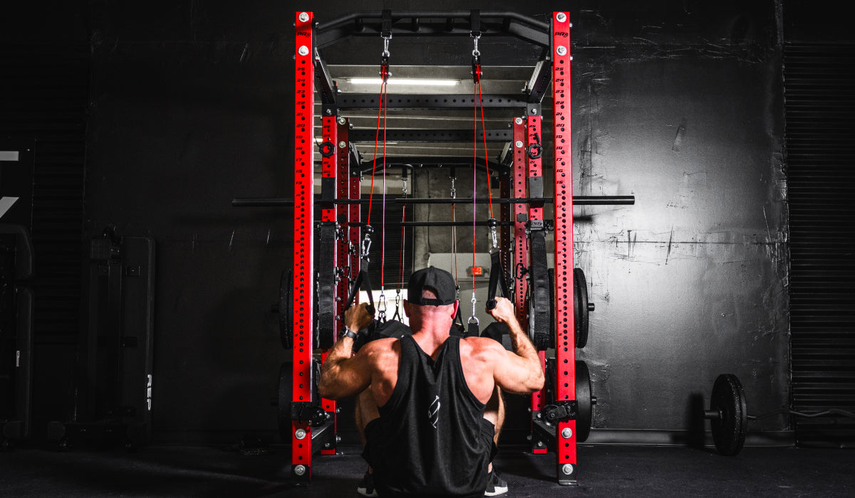 Man using a home gym power rack with resistance bands for a workout. Strength training with adjustable equipment in a modern, home gym setting.