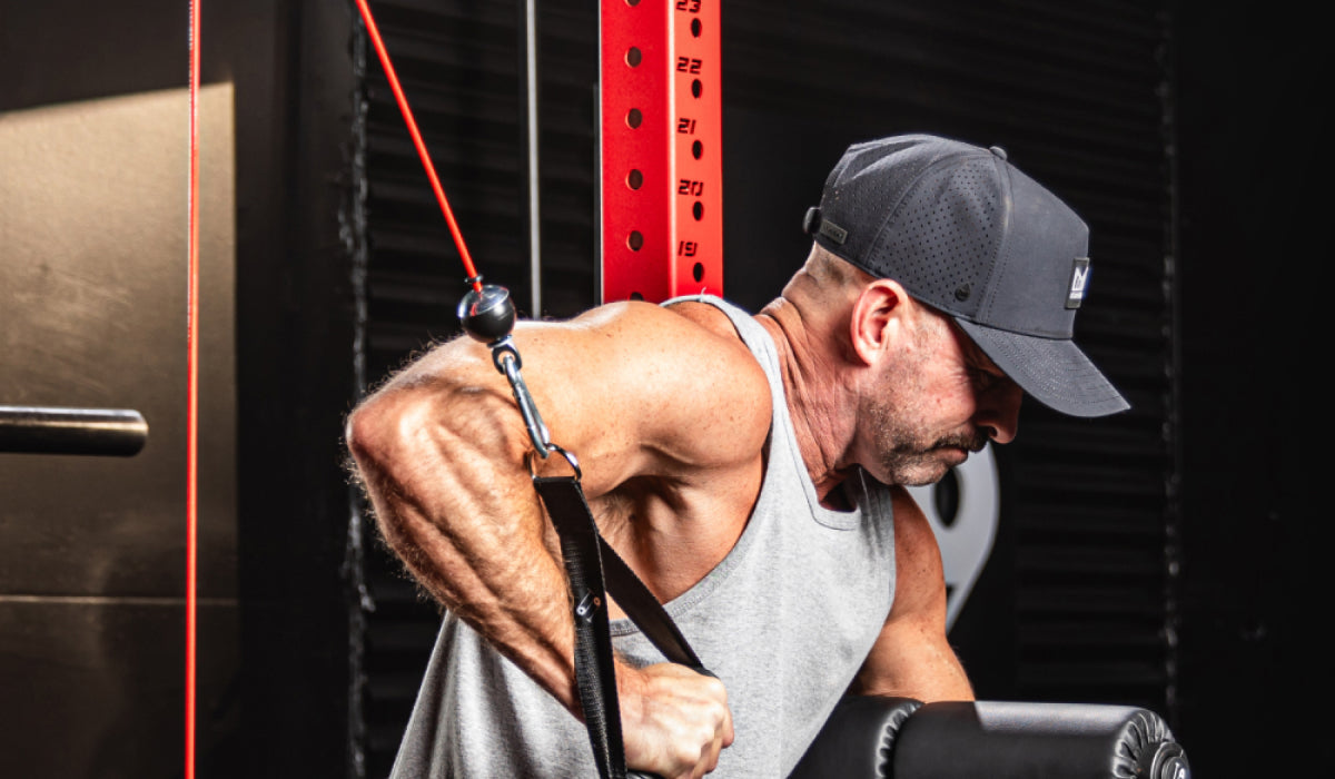 Man performing tricep pushdown exercise using red cable pulley system in home gym