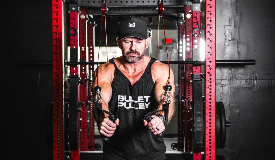 Man performing a cable chest fly workout in a home gym, focusing on building chest muscles using resistance cables and strength training equipment.